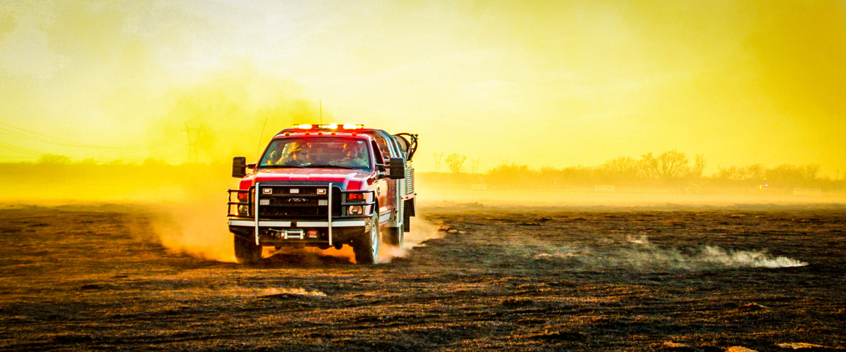 Firemen driving on field that was recently burned.